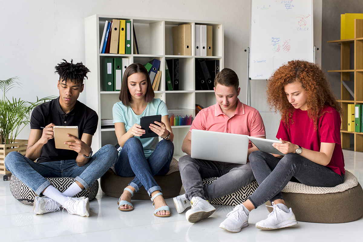 multiracial friends studying with electronic gadgets books sitting study room